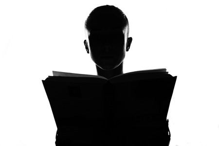 Female person silhouette with book,back lit lightの写真素材