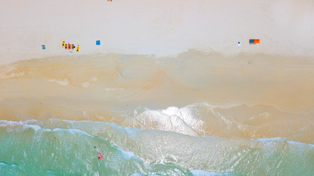 Aerial : Overhead  of people enjoying the summer at sand  beach ,waves breaking against the coast lineの写真素材