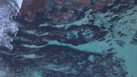 Above the ocean, aerial lock down view at foaming waves and surface near coast lineの写真素材