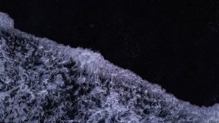 Aerial lock down view: Above the ocean, waves and water surface above coast lineの写真素材