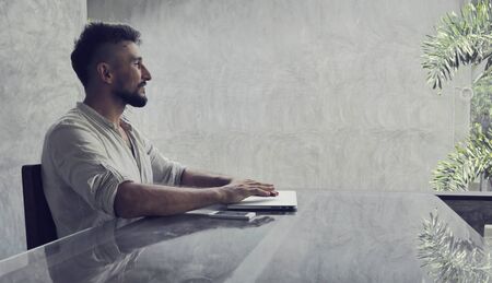 A satisfied man at laptop smile after done work on desktop computer in the home officeの写真素材
