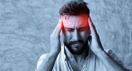 A man suffering headache from a painful head pain  and looking tired, worried and stressful