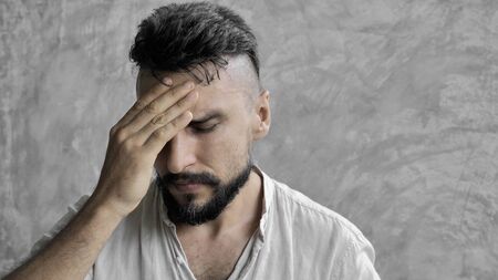 A man suffering headache from a painful head pain and looking tired, worried and stressfulの写真素材