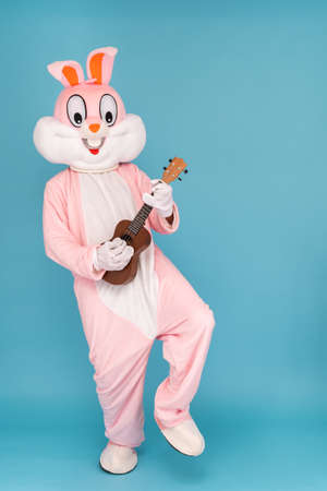 Crazy guitarist is playing music by ukulele or Hawaiian guitar. Easter bunny or rabbit or hare...