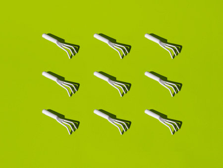 Gardening and time to plant vegetables texture. Small garden hand rake isolated on green background.