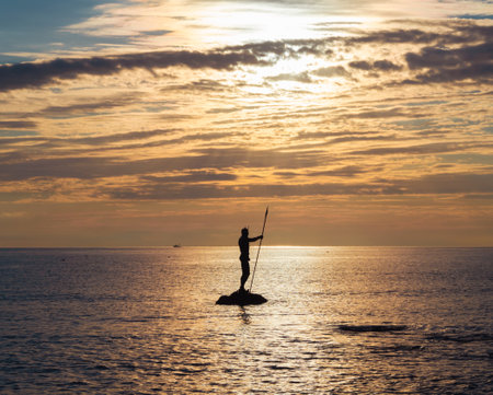 Sea freight, sea holidays. Neptune or Poseidon statue stands in sea at sunsetの写真素材
