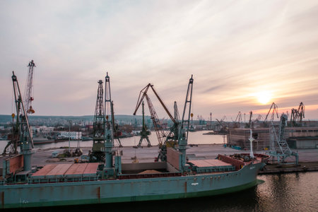10 April, 2023 Black Sea Port: Black Sea Grain Initiative 2023 grain Deal. Drone shot - loading grain into holds of sea cargo vessel with crane. Bunkering of dry cargo ship with grainのeditorial素材