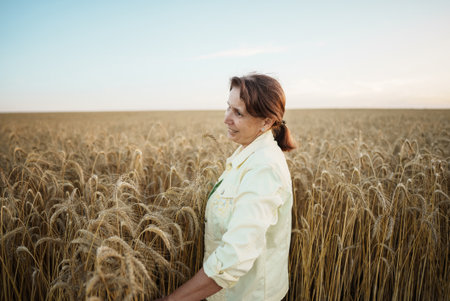 Agronomist walks through the field and enjoys the wheat harvest, woman cheking summer harvest. Wholesale grain trading on futuresの写真素材