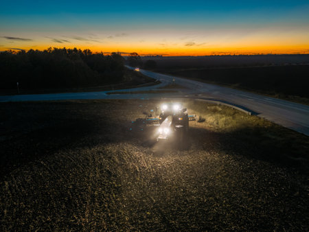 Agriculture and agribusiness. Aerial tractor with headlights on at duskの写真素材