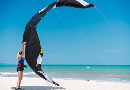 Young woman kitesurfing teacher holding a kite on a beach, water sports, activities. Kitesurfing school camp in Egyptの写真素材