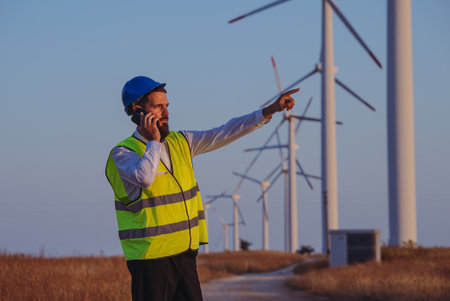 Technician worker point to side with wind turbines on the background