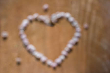 Unfocused heart made of gentle pink petals on cracked brown wooden backgroundの写真素材