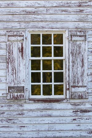 old window with fall trees reflecting in glass