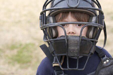 a young boy in baseball catchers maskの写真素材