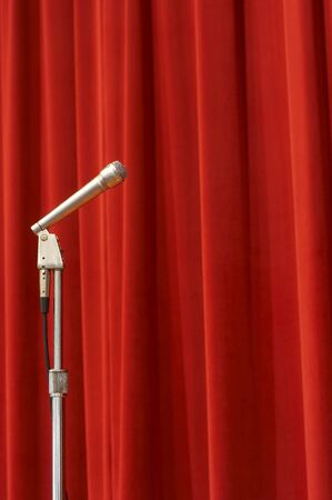 a crome microphone on a stage in front of a red curtainの写真素材