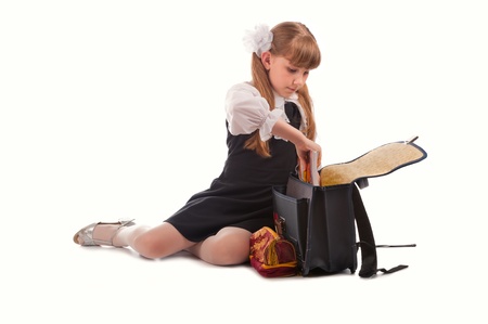 Cute young girl in uniform parking school bag; isolated on white backgroundの写真素材