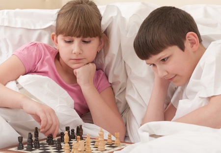 brother and sister play chess in bed, indoorsの写真素材