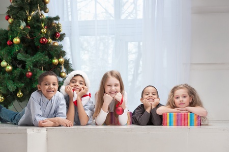 Happy children holding Christmas gifts and sitting on the floorの写真素材