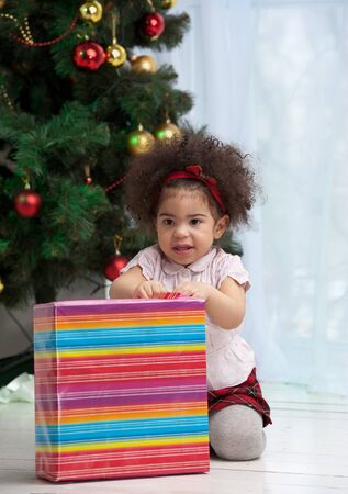 Girl holding Christmas gifts and sitting on the floorの写真素材