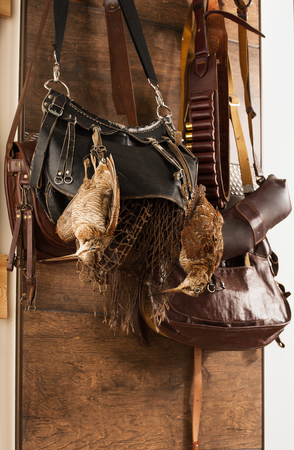 Hunting trophies and equipment hang on wall. Hunting of woodcock birds. Vertical.の写真素材