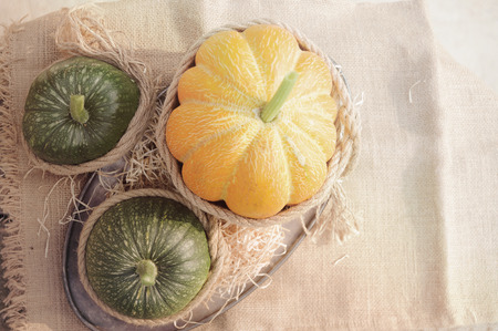 One orange pumpkin and two green pumpkin on the wooden table decorated burlap and rope. Outdoors.の写真素材