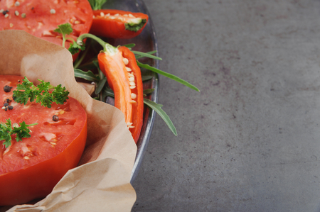 Two slice large red tomato on metal dish against a background of gray concrete. Horizontal.の写真素材