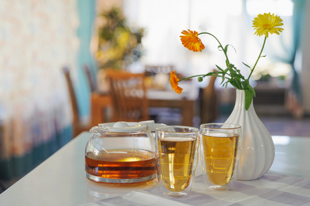 Two cups of calendula (marigold) tea on a table, with fresh flowers. Indoors. Horizontal.の写真素材