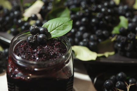 Jam from black chokeberries ( Aronia melanocarpa ) and its berries on dark table. Homemade preserves. Horizontal.の写真素材