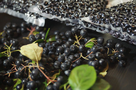 Chokeberry berries ( Aronia melanocarpa ) are packed in vacuum bags and black berries on dark table. Horizontal.の写真素材