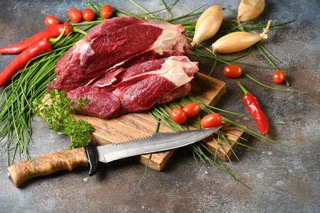 Fresh dark meat with ingredients for cooking on brown wooden cutting board. Hunting composition. Wildanimal hunting.の写真素材
