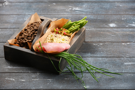 Special pet food VS natural pet food. Ingredients turkey, groats, rise, greens and sprouts in brown wooden box on rough dyed wooden background. Flat lay.の写真素材