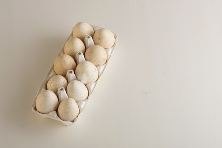 Ten turkey eggs with white paper box. Light wooden background.の写真素材