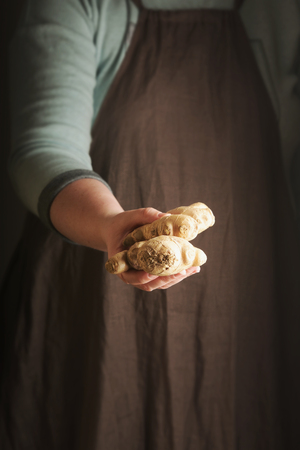 Woman holding a ginger in hand. Rustic style. Vertical.の写真素材