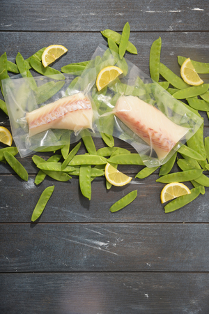 Sous Vide cooking concept. Vacuum packed ingredients arranged on wooden dyed background. Top View.