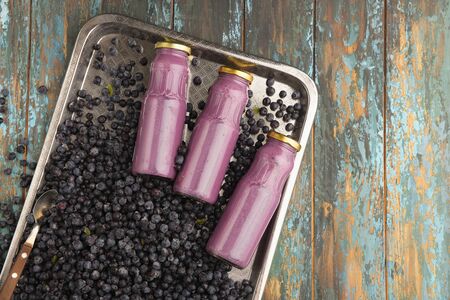 Yogurt in glass bottles is located on frozen blueberries. Top view.の写真素材