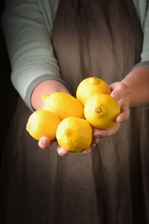 Organic fresh harvested fruits. Farmers hands with fresh lemon, closeup.の写真素材