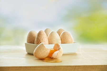 Six Turkey eggs and one broken on the kitchen Board against the window.