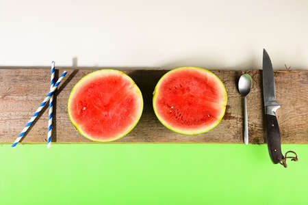 Cut watermelon with tubes as a cocktail on a wooden boardの写真素材