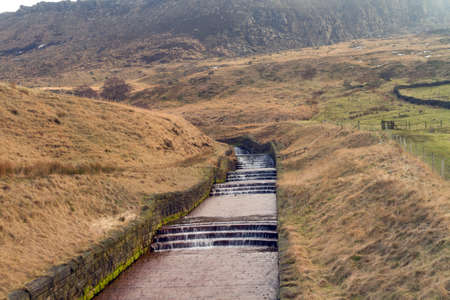 Water overflow at Dovestone reservoir with hills in the backgroundの写真素材