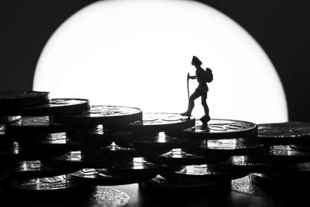 Miniature person mountaineering on coinsの写真素材