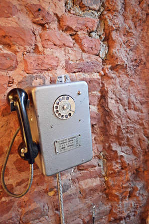 Grungy urban background of a brick wall with an old out of service payphone on itの写真素材