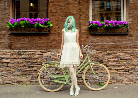 Young sexy girl in a white dress standing near a green retro bicycleの写真素材