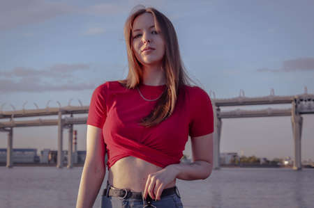 beautiful happy girl with long brown hair by the bay. against the background of the sea. in a red blouseの写真素材