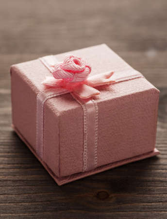 Pink small gift box with bow on a wooden table, closeup shot, selective focus, verticalの写真素材