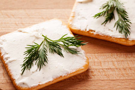 Crackers with spread cheese and dill on a wooden tableの写真素材