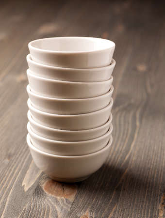 White ceramic stacked empty bowls on old wooden table, verticalの写真素材