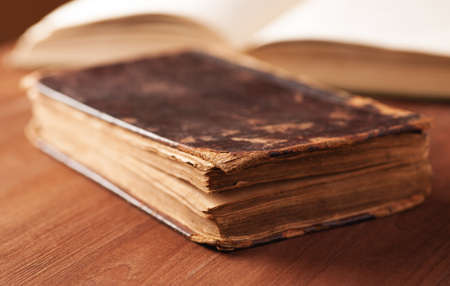 Old book in a leather cover on wooden table close up macro shot