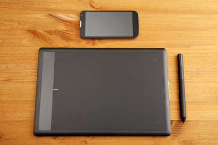 Graphic tablet and mobile gadget on wooden table. Top viewの写真素材