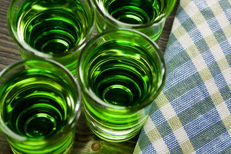 Green drink in shots on wooden table, closeup, selective focus