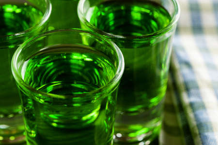 Green drink in shots on wooden table, closeup, selective focusの写真素材